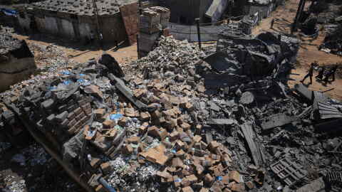 Palestinians walk past a food-aid warehouse damaged in an Israeli airstrike that targeted a nearby house in Deir al-Balah, central Gaza Strip, Wednesday, Aug. 26, 2026.