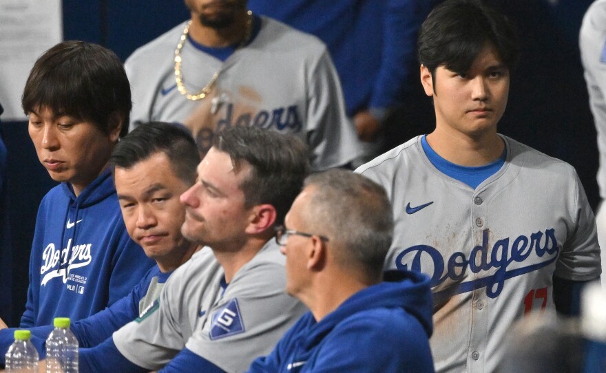 Baseball star Shohei Ohtani (right) and his interpreter, Ippei Mizuhara (left), are seen in the dugout in the 2024 MLB Seoul Series game between the Los Angeles Dodgers and the San Diego Padres. The Dodgers have fired Mizuhara after Ohtani's representatives claimed he was the victim of "a massive theft."