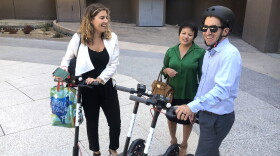 Three people stand by Bird electric scooters near Civic Center Plaza downtown, Sept. 18, 2018.