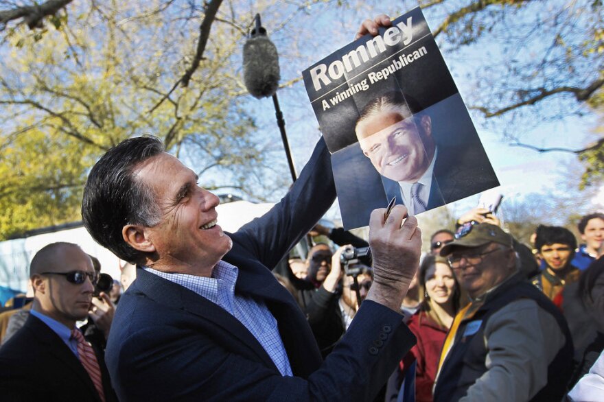 Mitt Romney holds a poster of his father, given to him at a campaign rally in Spartanburg, S.C., in January.