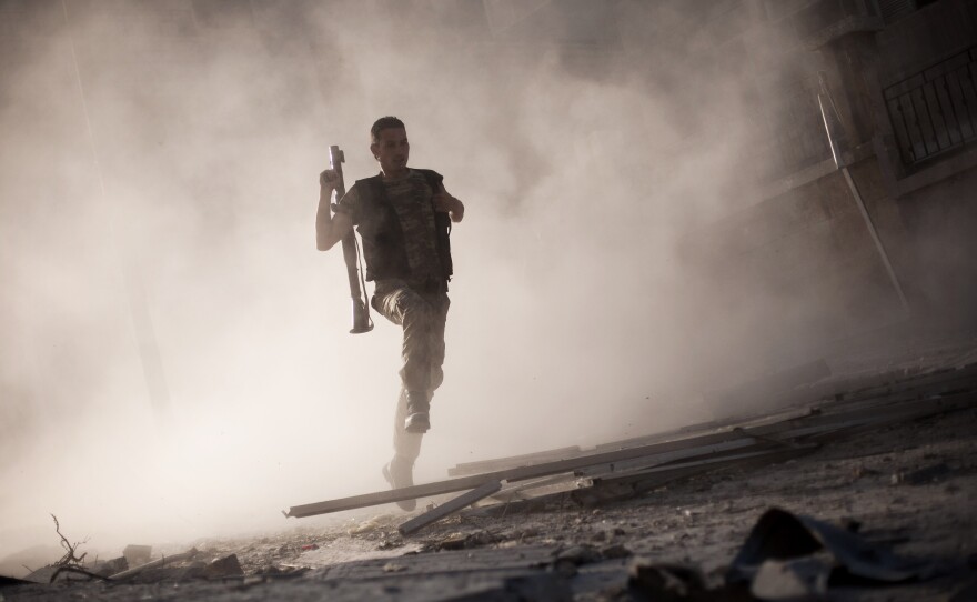 A Free Syrian Army fighter runs after attacking a tank with a rocket-propelled grenade during fighting in Aleppo, Syria, in September 2012. The rebels say they are willing to take on the Islamic State, but need more weapons.