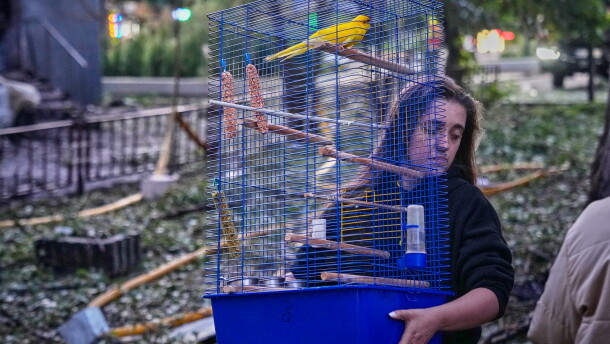 A woman carries a cage with a parrot as she leaves her damaged house following a Russia missile attack in Kyiv, Ukraine, Sunday, July 19, 2026.