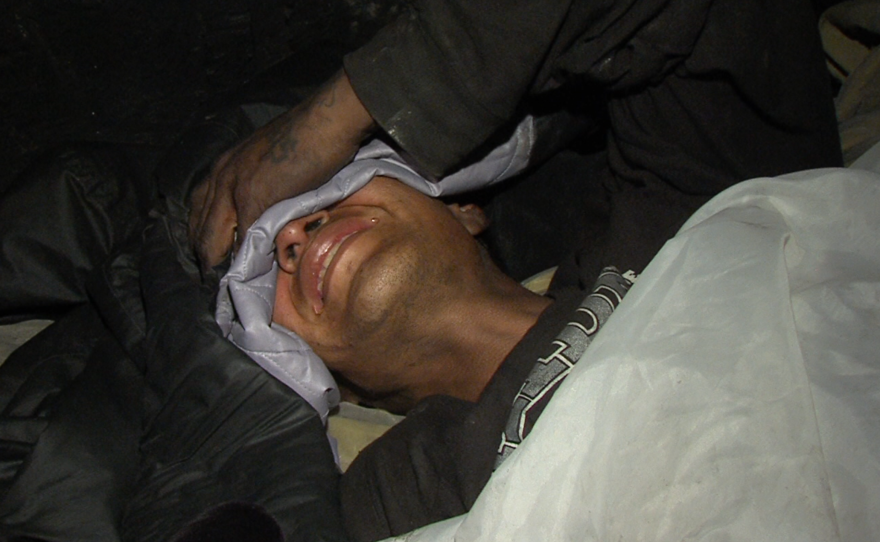 A Tijuana migrant grimaces in pain after he said he was hit by a car running from police, Jan. 15, 2016. 