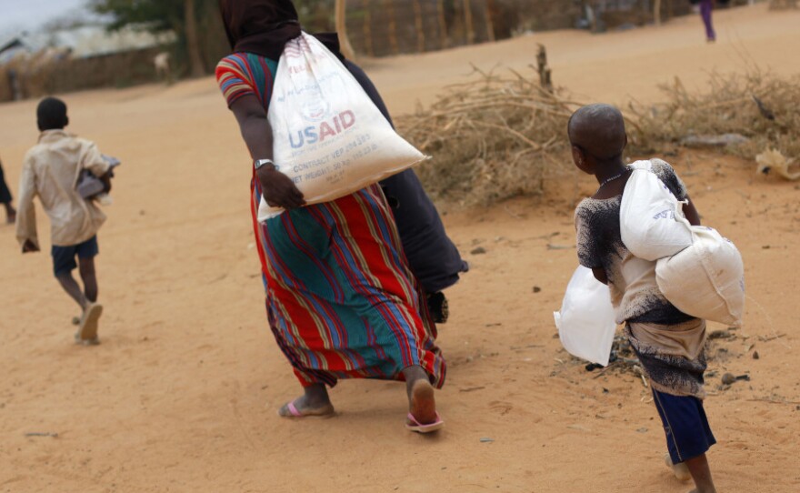 A Somali family carries their supply of food aid as they arrive at a refugee camp outside  Dadaab in northeastern Kenya along the Somali border, Aug. 5, 2011.