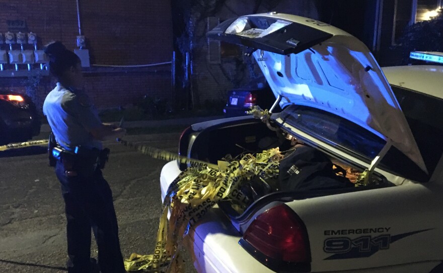 A New Orleans police officer strings up used crime scene tape at the scene of a drive-by shooting in the Central City neighborhood. One hundred people were shot in New Orleans by Feb. 10 — about a month sooner than recent years.
