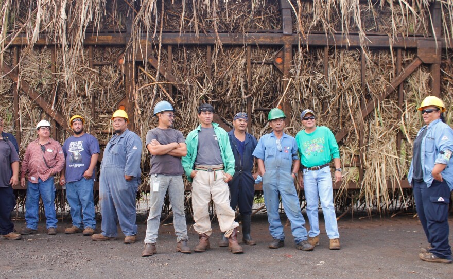 Some of the remaining workers at the mill stand in front of the last hauler truck of Hawaiian sugar cane.