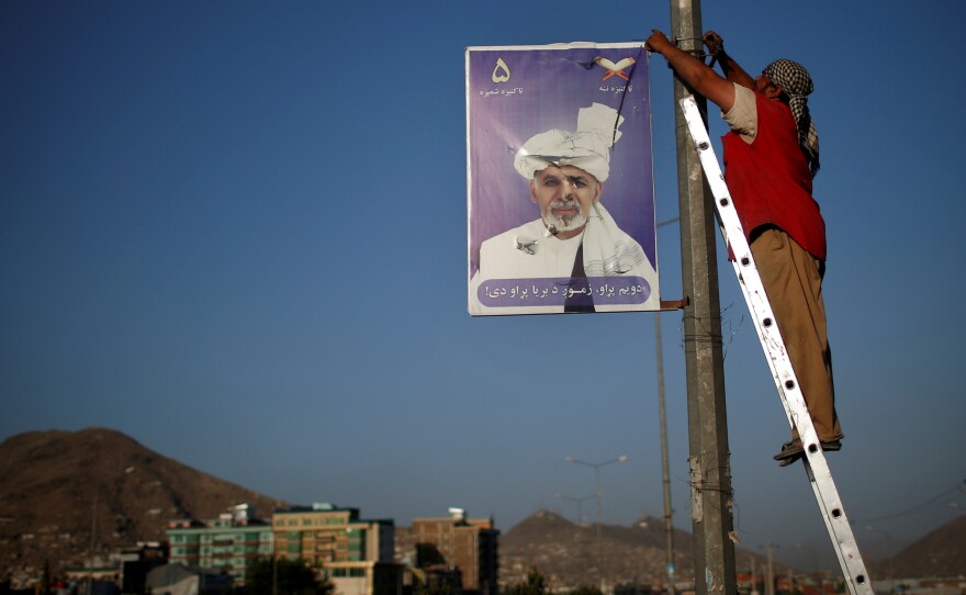 A man removes a poster of presidential candidate Ashraf Ghani after the official end of the election campaign. Saturday's runoff election pits Ghani against Abdullah Abdullah. Both have held top government positions and want close ties with the U.S.