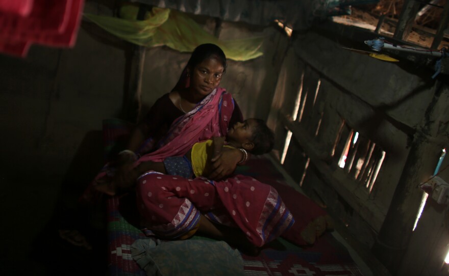 Arati Sardar, sits in her house with baby Sridoy. One of the family's goats was taken and eaten by a tiger, but having electricity now helps keep the home safer.
