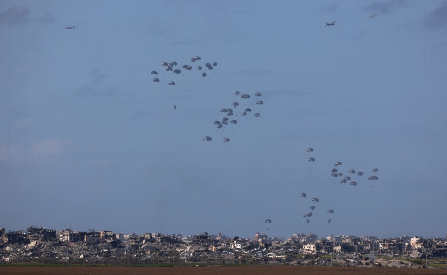 Humanitarian aid falls from planes over northern Gaza as seen from Israel's southern border with the Gaza Strip on March 7, 2024.