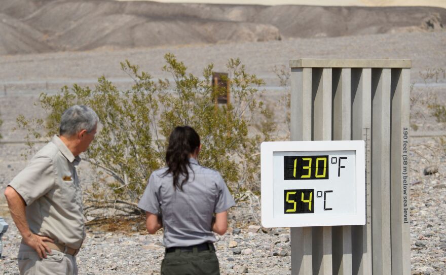 Park staff take pictures of a thermometer display showing a temperature of 130 degrees Fahrenheit on June 17 at the Furnace Creek Visitor Center at Death Valley National Park in California.
