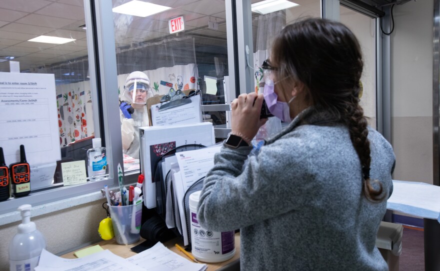 Two nurses in the pediatric intensive care unit at Children's National Hospital in Washington, D.C., communicate via walkie-talkie, as one helps on floor with COVID-19 patients and her colleague stands by to assist.