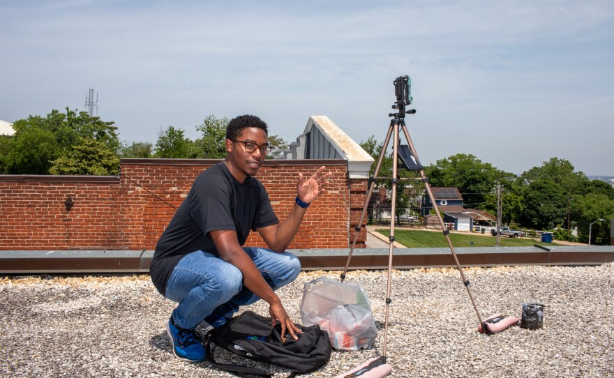 Researcher Matthew Aubourg checks an air monitor he installed on the roof of a car detailing shop in the Curtis Bay neighborhood of Baltimore, Md. The shop is right next to a railroad facility where trains unload carloads of coal, releasing dust into the air.