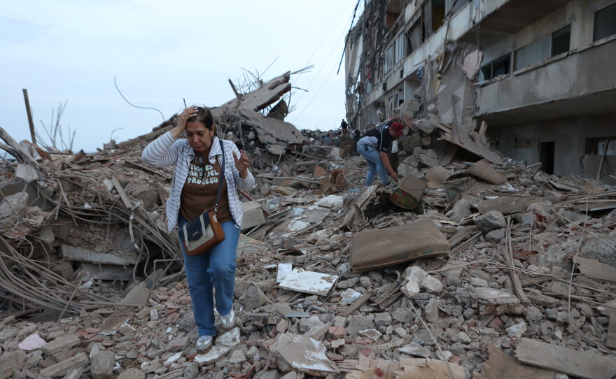 Residents walk among the rubble of building damaged in earthquakes the previous day in Catia La Mar, Venezuela.