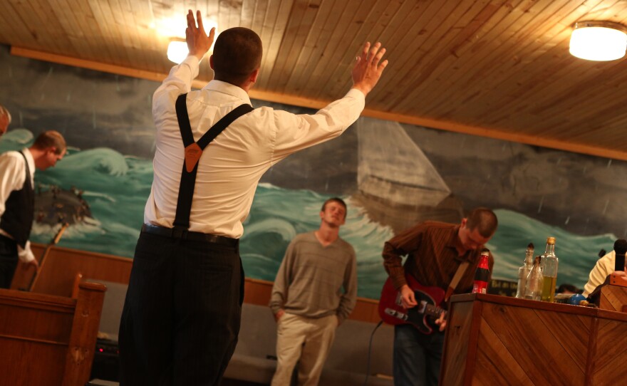 Jacob Grey raises his hands in Pastor Andrew's church.