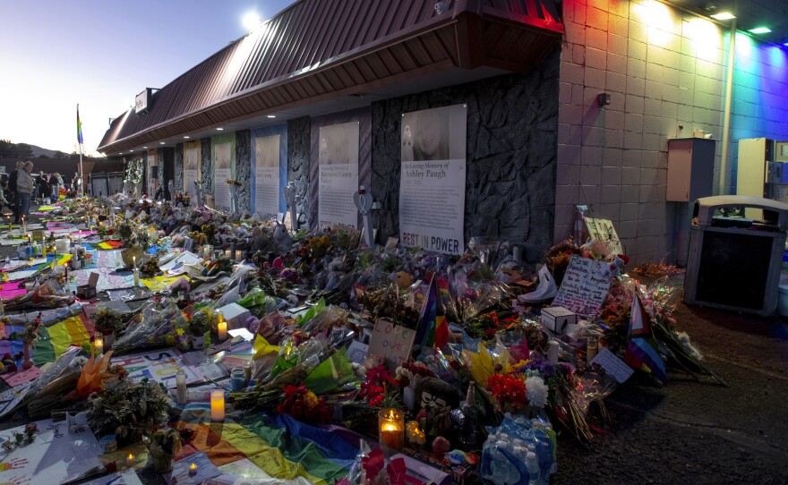 Mourners gather outside Club Q to visit a memorial, which has been moved from a sidewalk outside of police tape that was surrounding the club, on Friday, Nov. 25, 2022, in Colorado Spring, Colo.