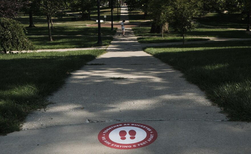 A sign on the ground at The Ohio State University reminds students to practice social distancing. The university has issued more than 200 interim suspensions to students linked to off-campus parties.