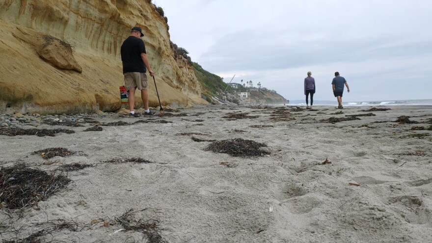 Mark O'Connor walks along Moonlight Beach picking up trash in Encinitas, Calif. Oct. 7, 2021.