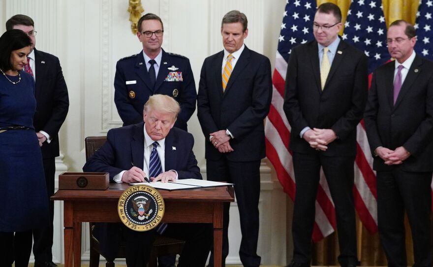 President Trump, surrounded by federal officials on Thursday, signs a proclamation for Older Americans Month during an event on protecting seniors from the coronavirus.