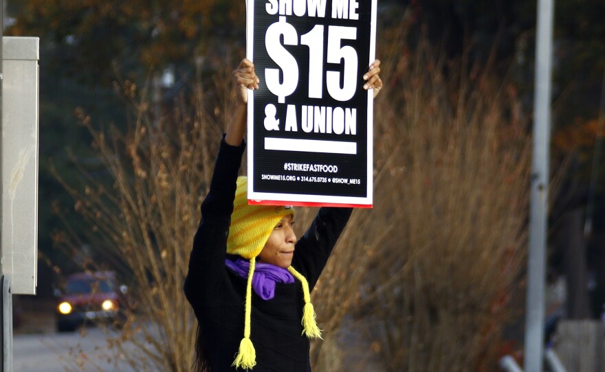 A protester demonstrates for higher wages for fast food workers in Jackson, Miss., in December. Employers are hiring more people, but overall, the wages they're paying remain flat.