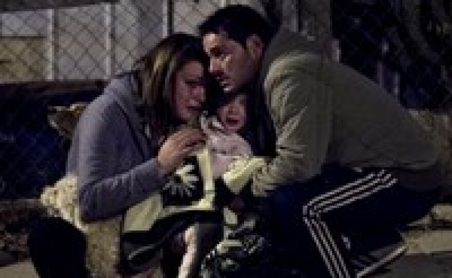 A couple and their baby take temporary refuge after a large fire reactivated in their district of Valparaiso, Chile, Sunday. More than 10,000 people were evacuated as an army of firefighters battled the blaze.