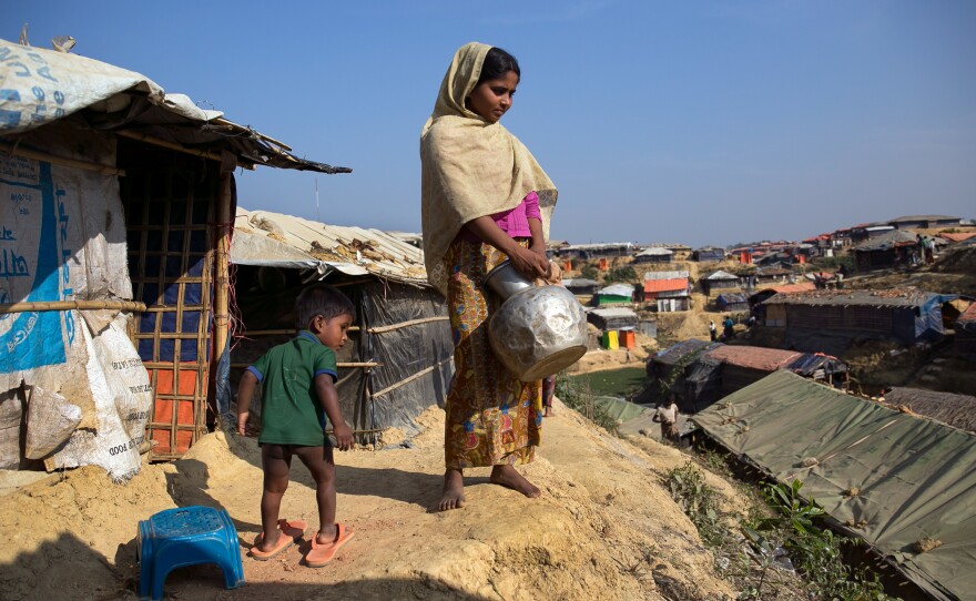 Sanura Begum stands with her son, Abdur Sobor, outside her plastic and bamboo shelter in the Kutupalong refugee camp in Bangladesh. One of the things she misses most about Myanmar is her family's wooden house.