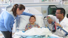 Eric Montaño is shown sitting in a hospital bed while his mother and doctor stand beside him in this undated photo. 