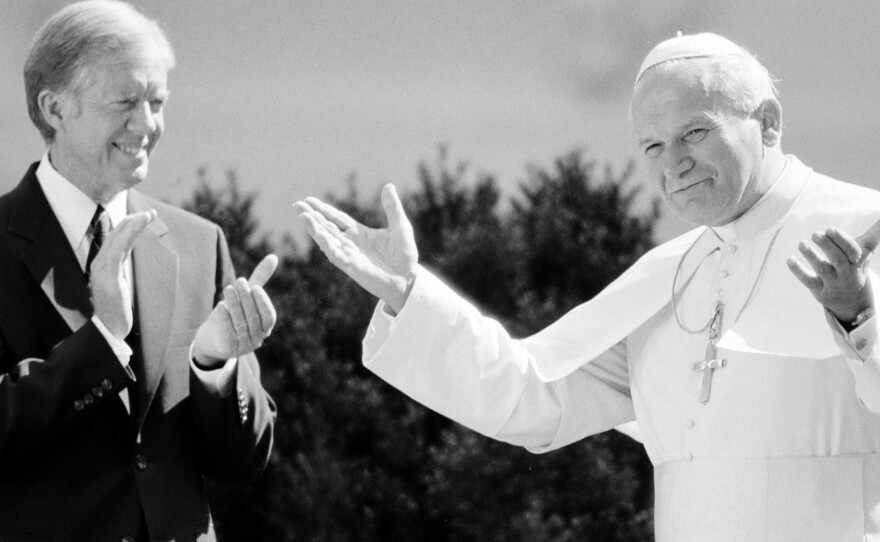 Pope John Paul II acknowledges applause from President Jimmy Carter and other dignitaries as the pontiff is welcomed to the White House on Oct. 6, 1979.
