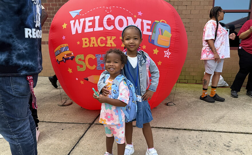 4-year-old Olivia Person stands outside Charles City Elementary on her first day of school with her 2-year-old sister Aria.