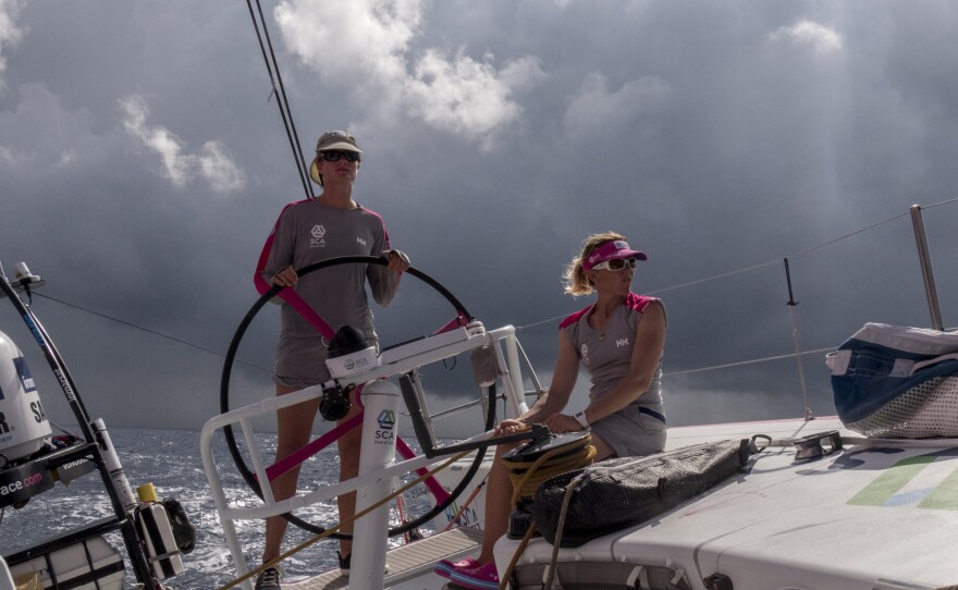 Leg 2 onboard Team SCA, in November 2014. Elodie Mettraux helms and Sam Davies trims main as a squal passes behind the boat.