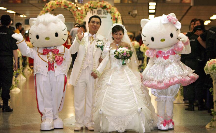 Jamie Ng (left) and Horlick Ng pose with Hello Kitty and Dear Daniel at Hong Kong's Mass Transit Railway during a "Hello Kitty Dream Wedding" in Hong Kong in 2007.