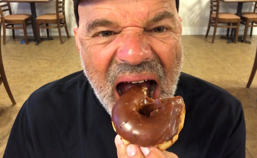 John Burnett's riding partner, Hawk Mendenhall, devours a chocolate donut.