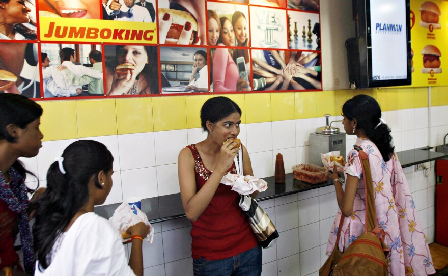 Young Indian women eat the popular food snack vada pav at a Jumboking outlet in Mumbai.