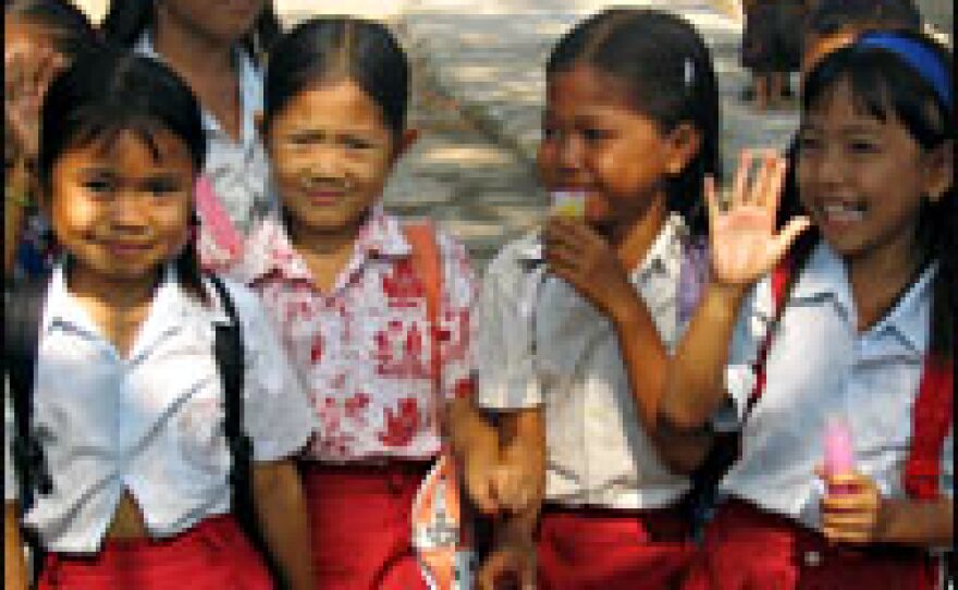 Indonesian girls on their way to school pause to check out the vaccination effort in their village.