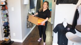 Heather Treviño carries a box of bandanas through the offices of Planet Apparel in San Diego on March 26, 2020.