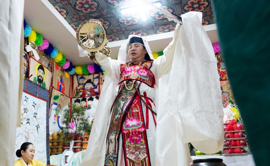 Shaman Jeong Soon-deok holds up a fan, bells and other ceremonial objects during an initiation ceremony at a temple in Seoul.