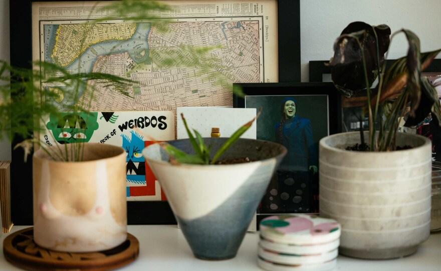A photo of Stickler as Elphaba in <em>Wicked</em> sits next to a framed map of New York City in Stickler's home in Chicago. Now a software engineer, Stickler previously worked as a Broadway performer.