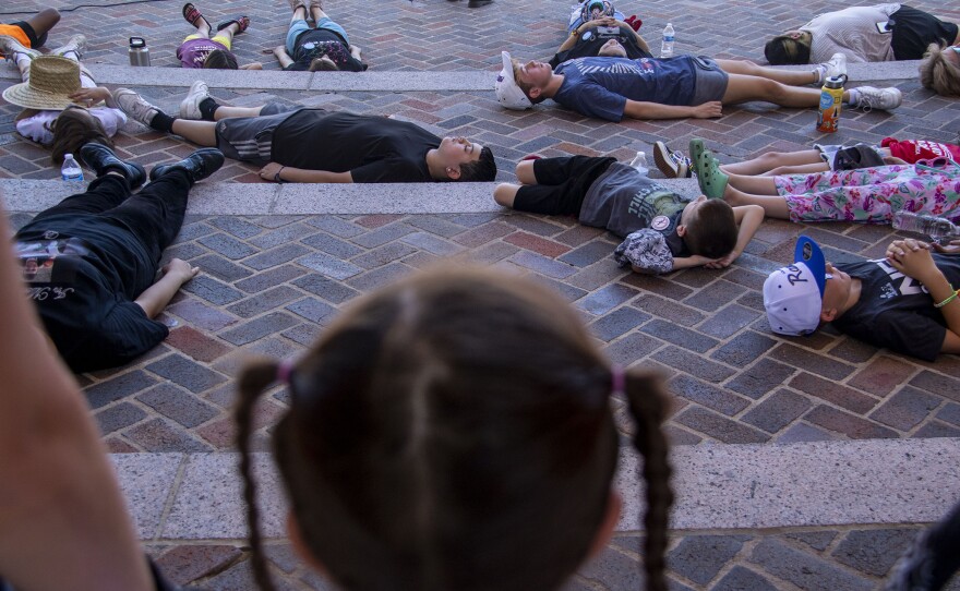 In Civic Center Park's Greek amphitheater, 21 children lie on the ground to represent 21 people killed in Uvalde, Texas, during the March For Our Lives rally.