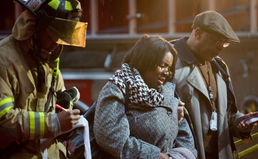 Smoke inhalation victims walk past a firefighter towards a medical aid bus Monday after passengers on the Washington, D.C., subway were injured when smoke filled the L'Enfant Plaza station during the afternoon rush hour.