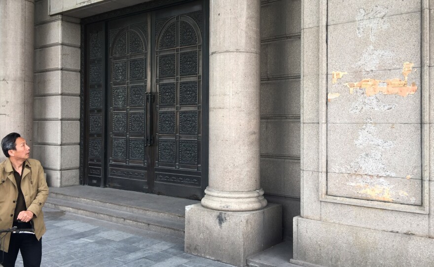 A pedestrian walks past the building on the Bund, Shanghai's colonial waterfront, that until recently held Zhongjin Capital Management. Police raided the firm earlier this month and arrested more than 20 company officials. The company signs have been torn down.