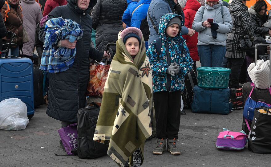People wait to board buses taking them further into Poland or abroad from a temporary refugee shelter in a former shopping center near the Polish city of Przemysl on Tuesday.