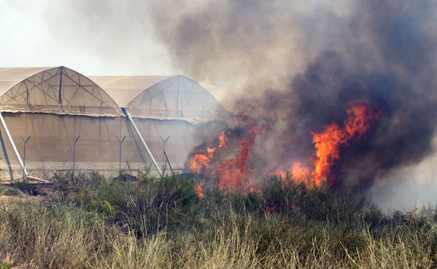 Fire consumes a field close to greenhouses on a farm in the Israeli Mediterranean coastal city of Ashkelon after a rocket fired by Palestinian militants from the Gaza Strip landed there.