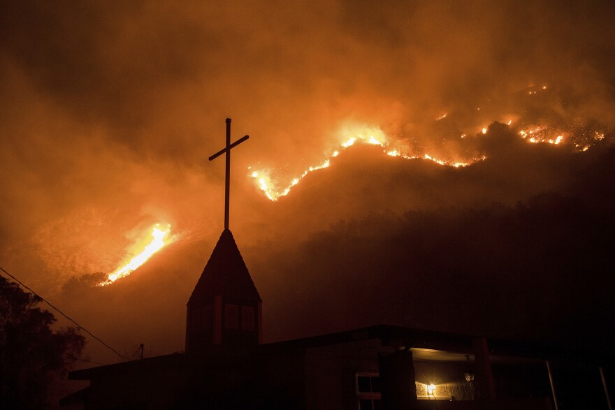 Flames from a wildfire advance down a hillside near the Springs of Life Church in Casitas Springs, Calif., on Tuesday, Dec. 5, 2017.