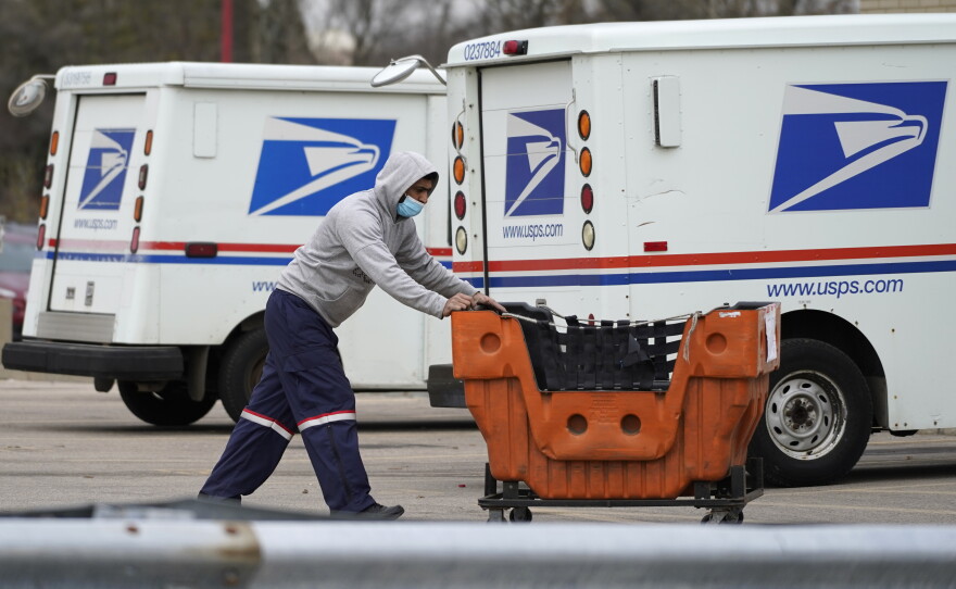 A U.S. Postal Service employee pushes a cart outside a post office in Wheeling, Ill., in 2021.