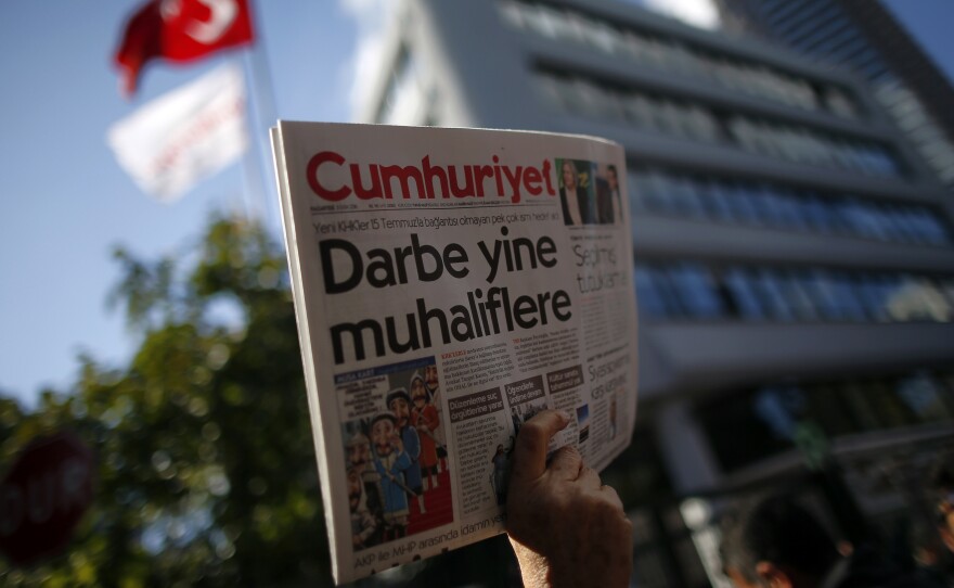 A man holds up the latest copy of Turkey's opposition Cumhuriyet newspaper outside its headquarters after Turkish police reportedly detained the chief editor and at least eight of its senior staff on Monday.