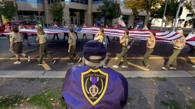 Army veteran Andy Zoglman, 77, watches an American flag pass by during a Veterans Day parade in Sacramento, on Nov. 11, 2023.