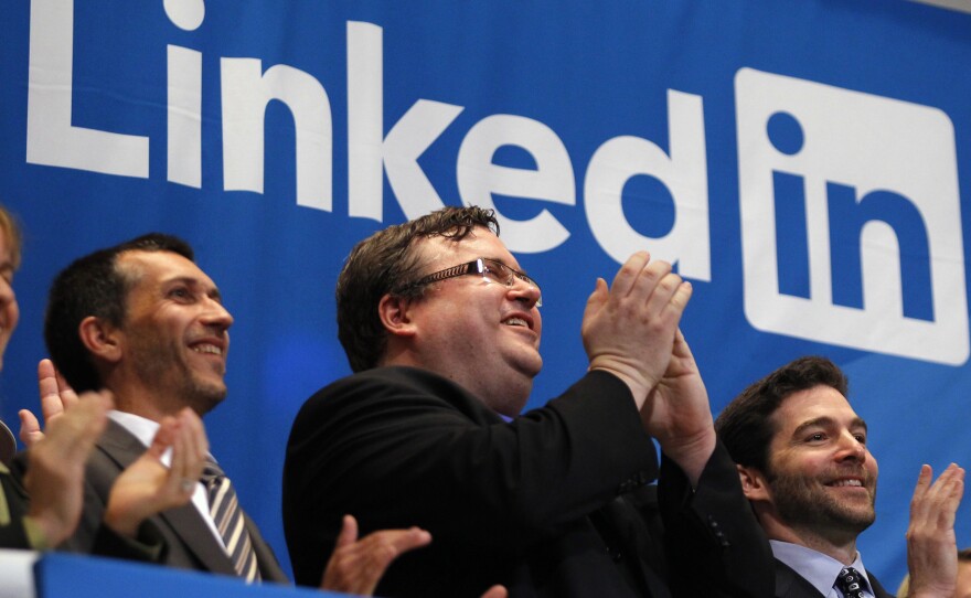 Reid Garrett Hoffman (center), the founder of LinkedIn, applauds from the bell balcony after the opening bell during the company's initial public offering at the New York Stock Exchange.