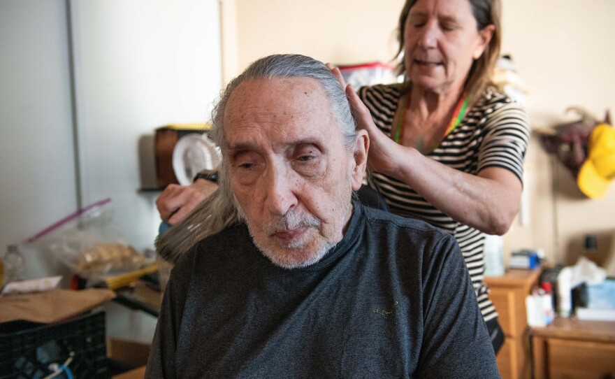 Leon Christiansen gets his long gray hair brushed by caregiver Patty Sterling on April 9, 2024.