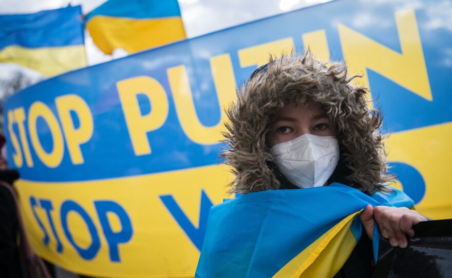 A protester stands in front of a banner reading "Stop Putin - Stop War" during a demonstration for peace in Ukraine in front of the Brandenburger Gate in Berlin on February 19.