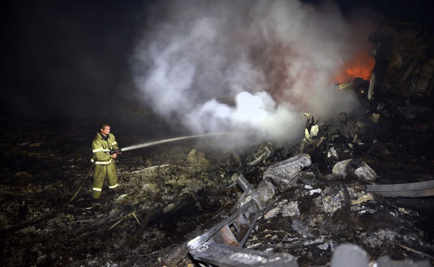 A firefighter douses the smoldering wreckage of Flight MH17 on Thursday.