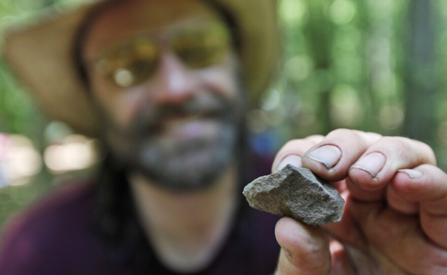 Daniel Sayers has been working for more than a decade in Great Dismal Swamp; here, in 2011, he displays a fire-cracked rock from a dig site. His new book pieces together the stories of those who once lived in settlements scattered on patches of dry land in the swamp.